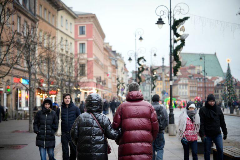 Ludzie spacerujący na ulicy w Warszawie przystrojonej na święta