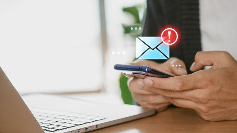 Osoba korzystająca z telefonu i laptopa przy biurku