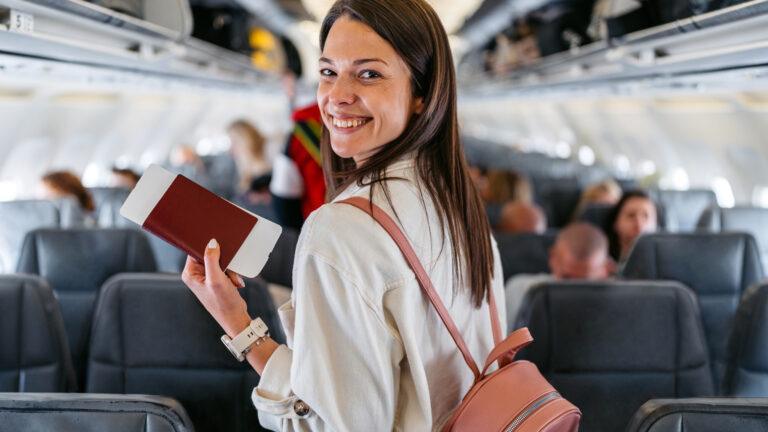 Młoda kobieta z bagażem podręcznym na pokładzie samolotu