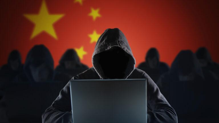 Okapturzona zanonimizowana osoba z laptopem na tle chińskiej flagi