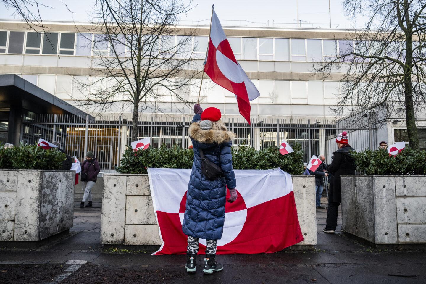 Osoba protestująca z flagą Grenlandii przed ambasadą amerykańską w Kopenhadze