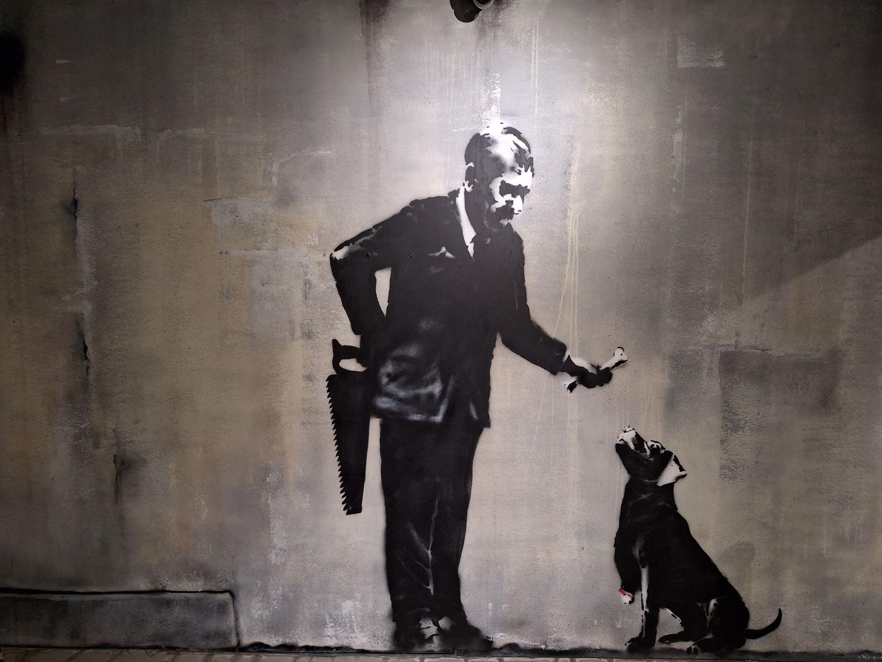 W pobliżu Uniwersytetu Sorbony Banksy pokazał psa karmionego kością przez człowieka, który za plecami trzyma piłę. 