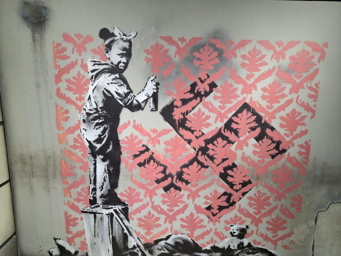 Graffiti Banksy'ego przedstawiające dziewczynkę zamalowującą swastykę