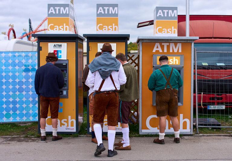 Mężczyźni w bawarskich strojach w kolejce do bankomatu