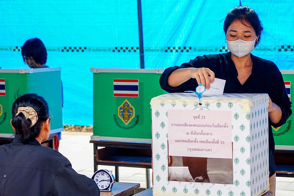 Kobieta w masce wrzuca kartę do głosowania do urny