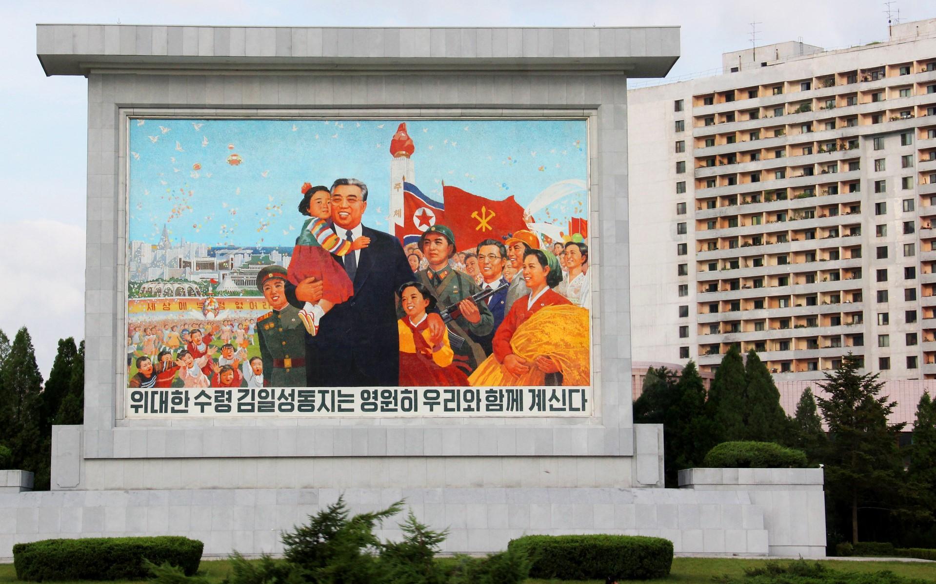 Wmurowana tablica przedstawiająca Kim Ir Sena w otoczeniu dzieci, wojskowych i innych osób