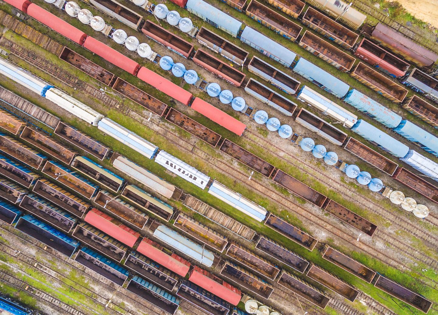 Colorful railway carriages seen from the air. Railway wagons placed in a row on parallel tracks.