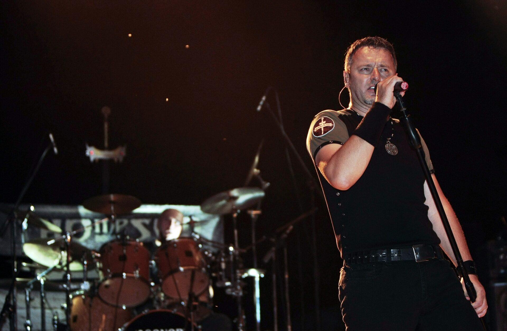 Marko Perković Thompson z mikrofonem podczas scenicznego występu.