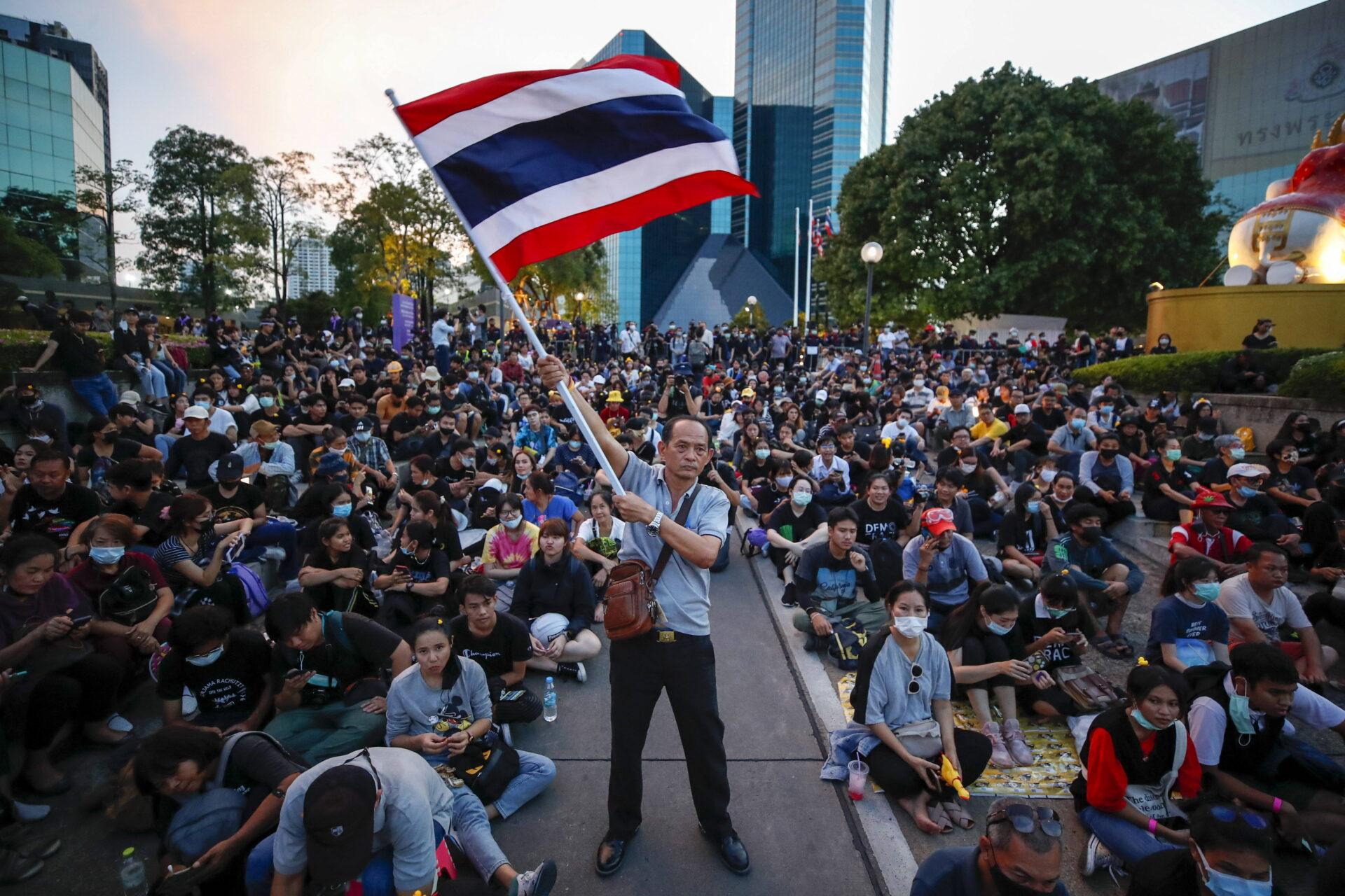 Mężczyzna z flagą Tajlandii na tle tłumu osób