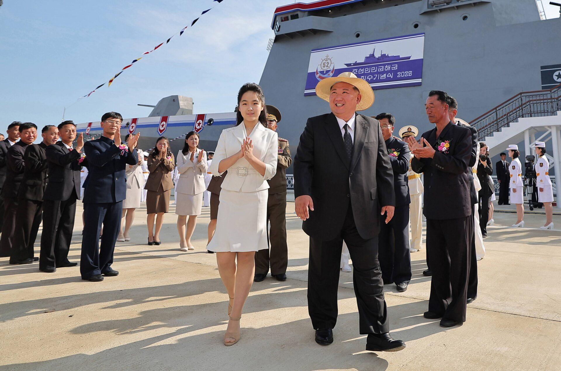Kim Dzong Un i Kim Ju Ae na nabrzeżu portowym oklaskiwani przez umundurowane osoby. W tle okręt wojenny 