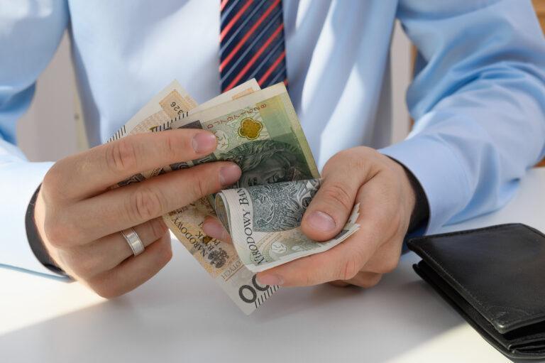 A man holds cash money in his hand, counting banknotes