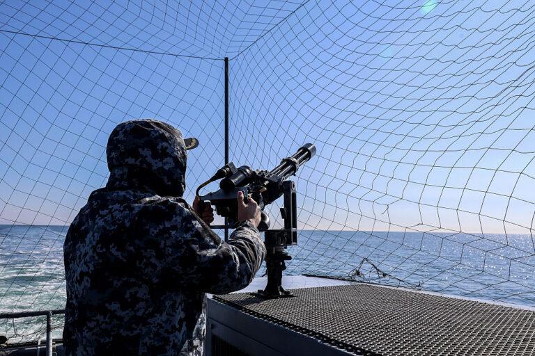 Żołnierz obsługuje działo na tle morza