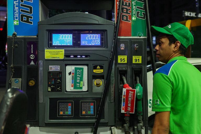 Pracownik stacji w zielonym uniformie przy dystrybutorze benzyny