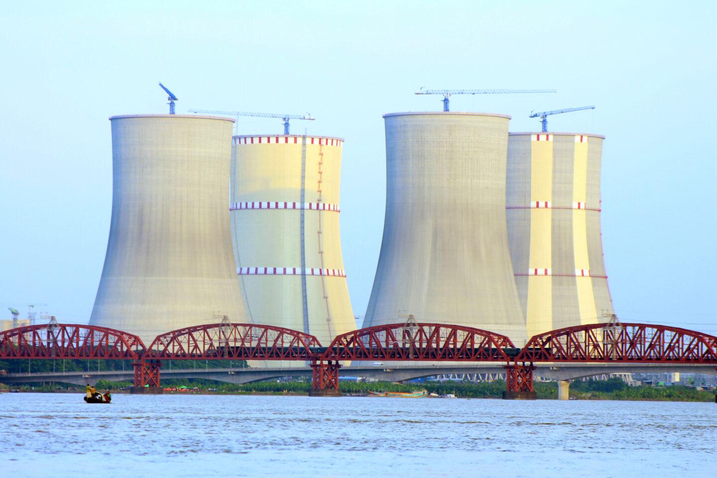 Cztery kominy elektrowni nad rzeką z mostem