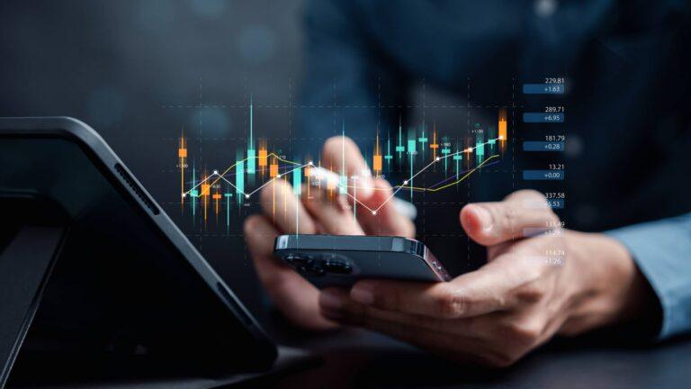 Osoba używająca telefonu na tle wykresu świecowego kursu