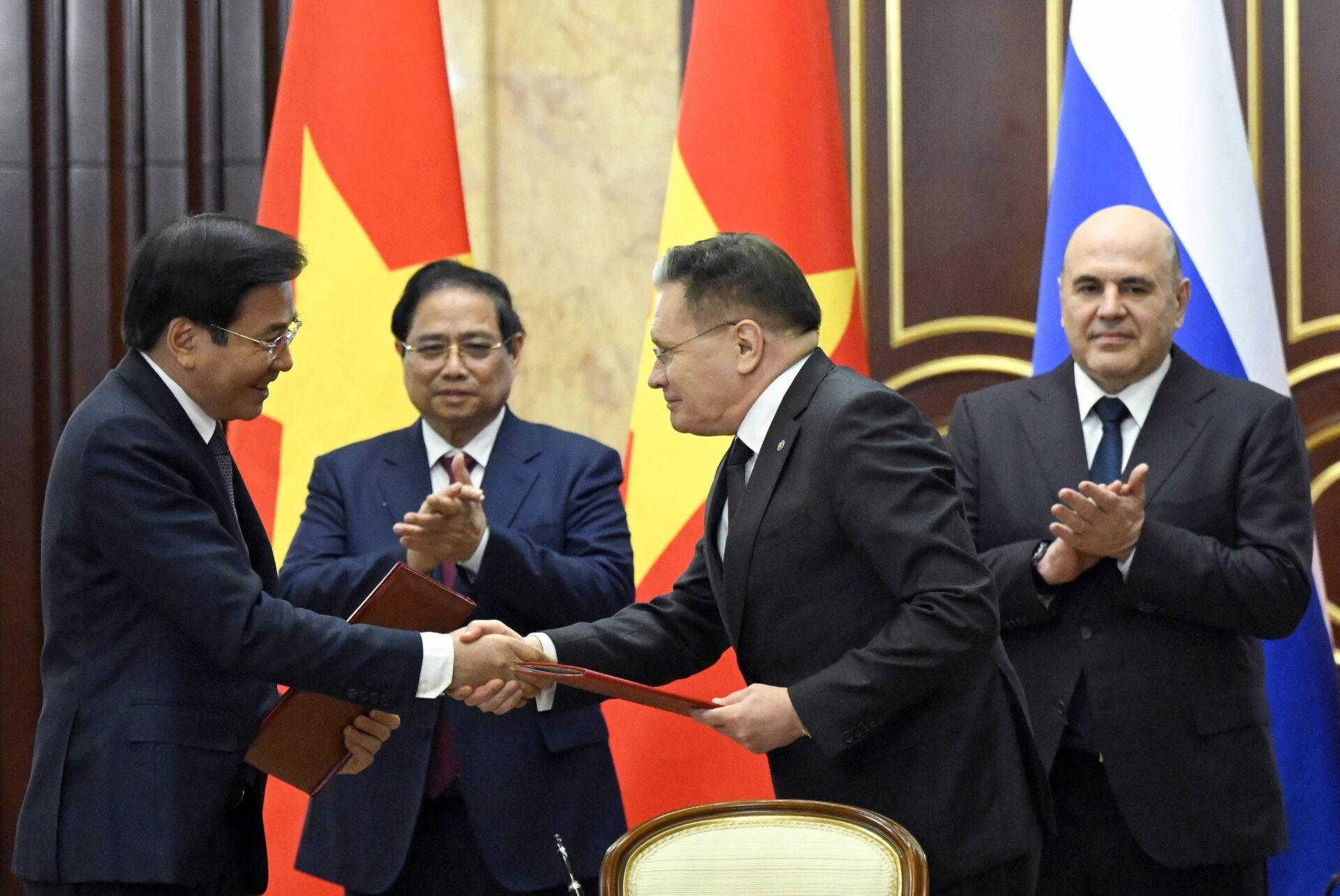 Grupa mężczyzn w garniturach na tle flag Wietnamu i Rosji