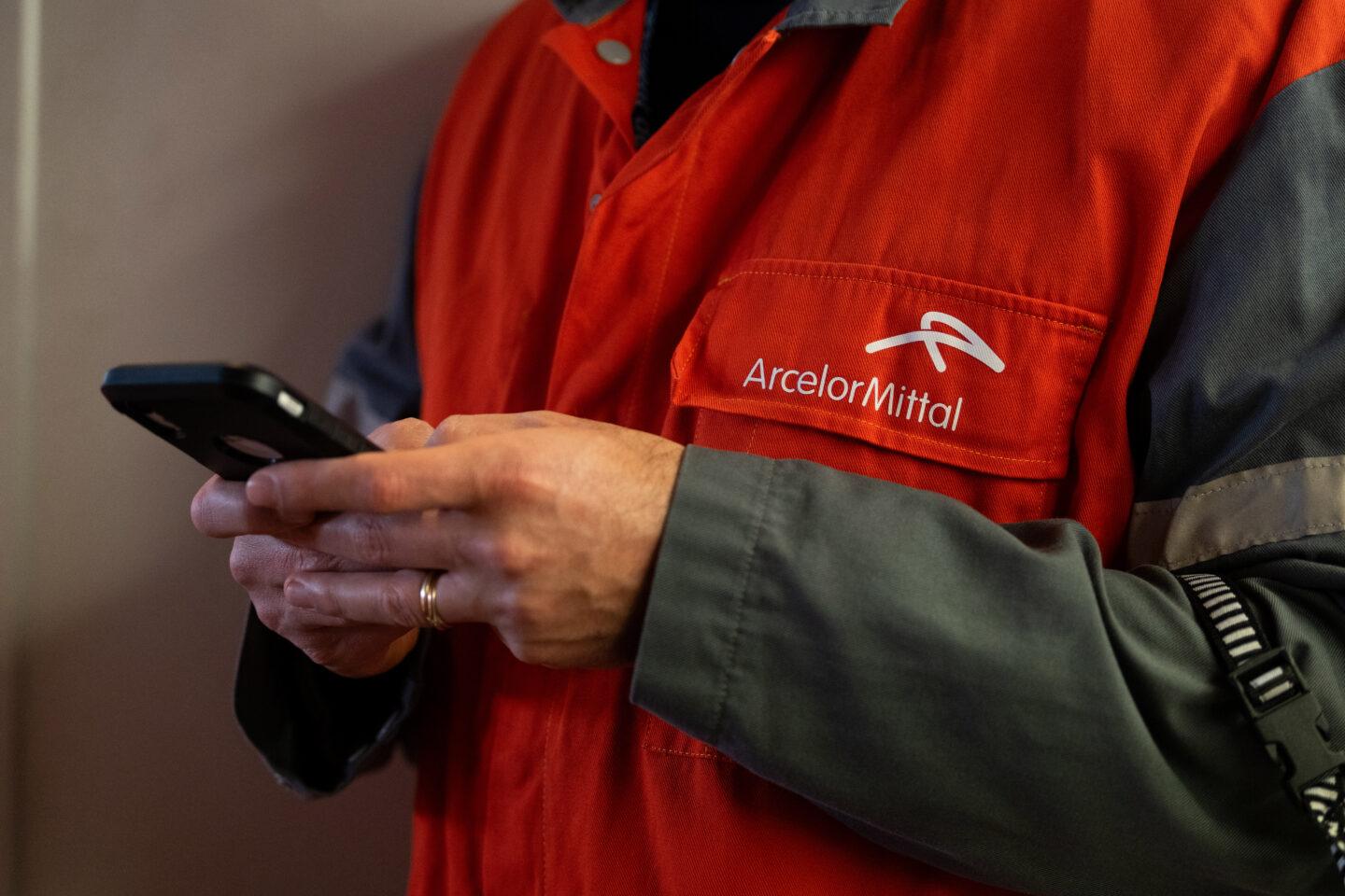 Pracownik w uniformie huty Arcelor Mittal z telefonem w ręku.