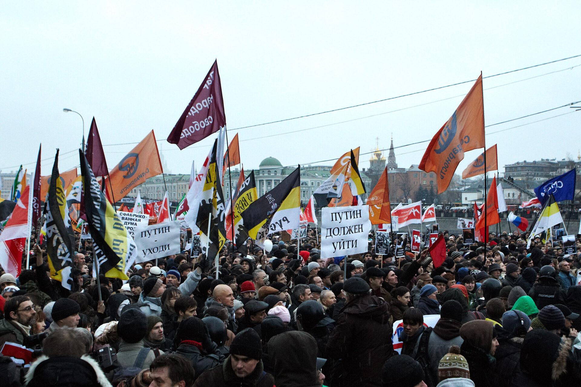 Protestujący przeciwko sfałszowanym wyborom do Dumy Państwowej 10 grudnia 2011 r. na placu Błotnym w Moskwie. Trzymają flagi i transparenty z napisami „Putin musi odejść” (ros. „Путин должен уйти”).