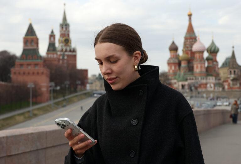 Spacerująca w pobliżu Kremla młoda kobieta trzyma w ręku smartfon i próbuje połączyć się z internetem.