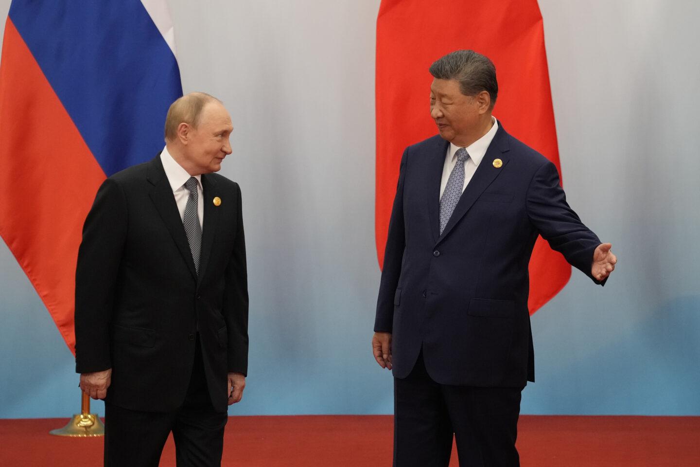 Xi Jinping i Władimir Putin stoją na tle flag Chin i Rosji