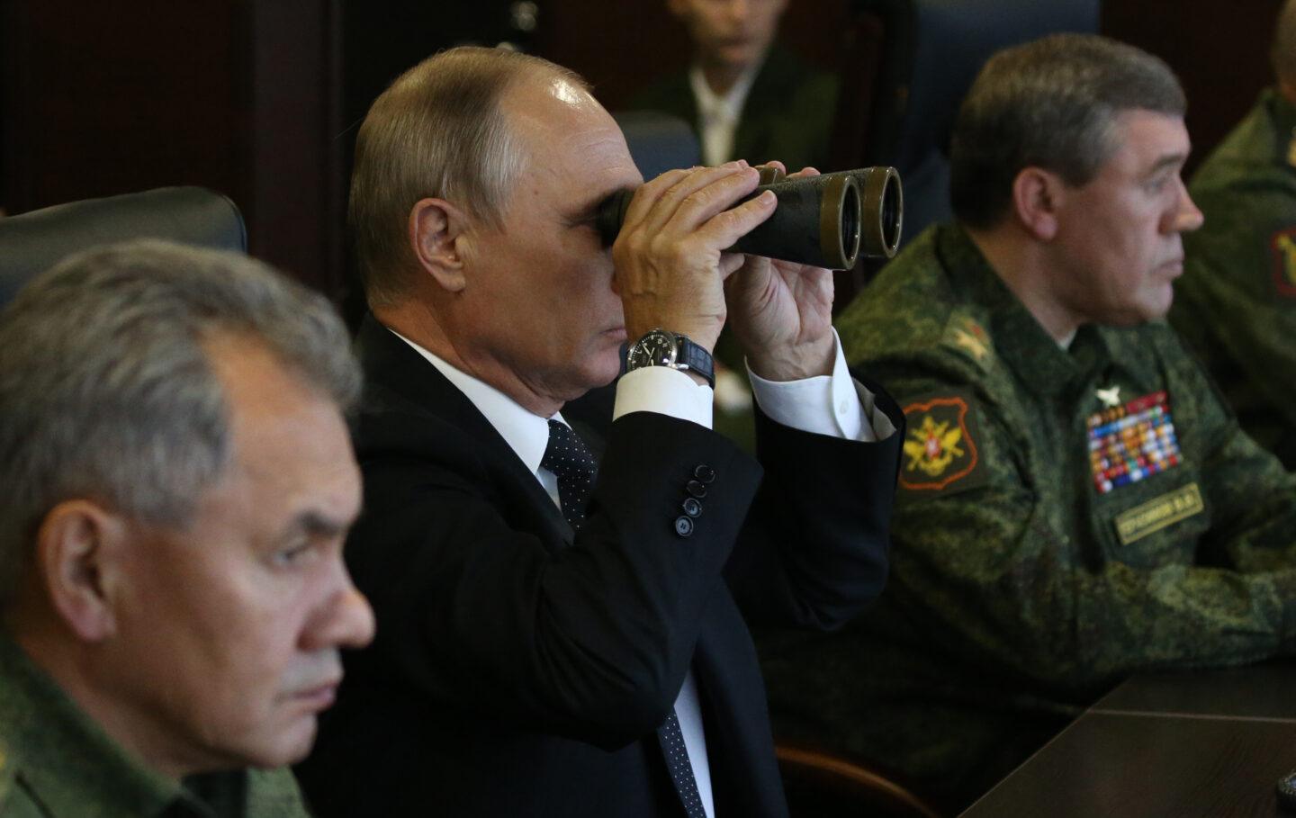 Prezydent Rosji Władimir Putin z lornetką w towarzystwie wysokich rosyjskich oficerów.