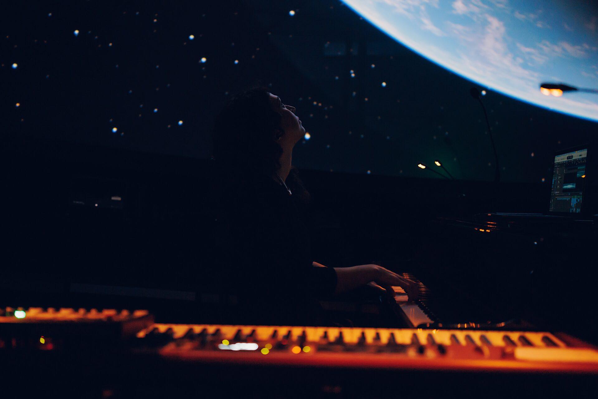 Zuzanna Całka grająca na tle projekcji z gwiazdami w Planetarium Centrum Nauki Kopernik
