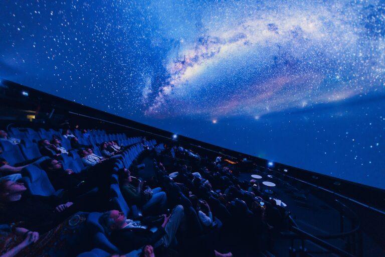 Ekran projekcyjny w Planetarium Centrum Nauki Kopernik z rozgwieżdżonym niebem i publiką