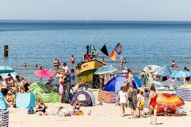 Plażowicze nad Bałtykiem na tle kutra