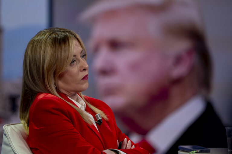 Premier Włoch Giorgia Meloni, a w jej tle rozmazany wizerunek Donalda Trumpa