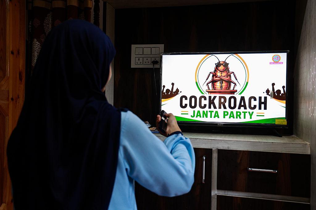 Osoba patrząc na ekran telewizora z logo Cockroach Janta Party