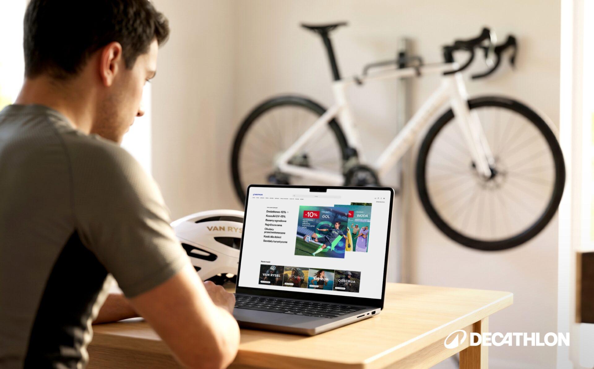 Mężczyzna siedzący w pokoju z rowerem na ścianie przed komputerem z otwartym serwisem internetowym Decathlon