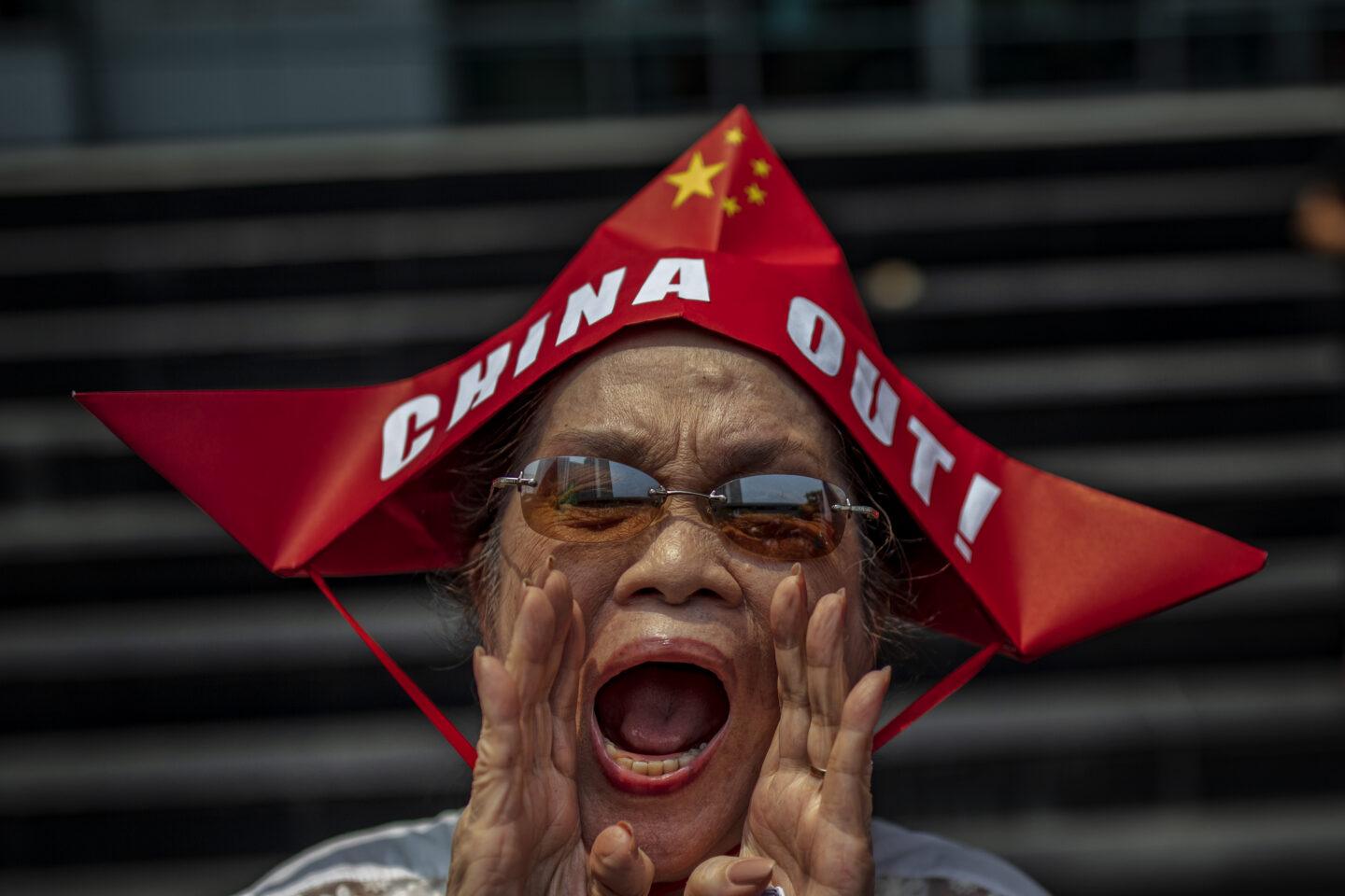 Kobieta w czerwonej czapce w kształcie łódki z napisem "China Out"