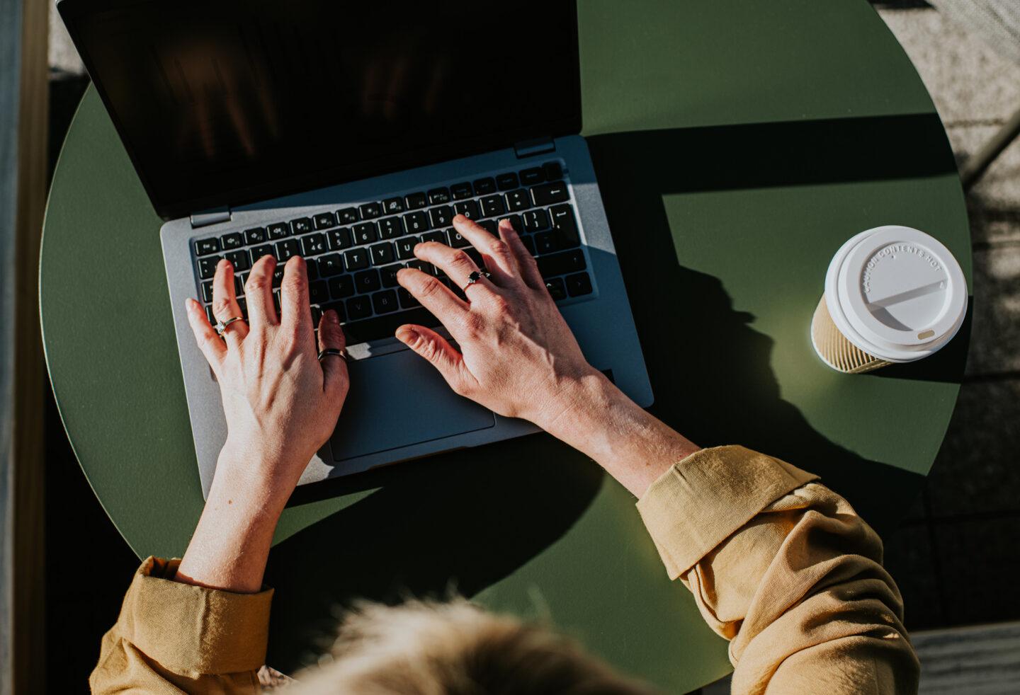 kobieta pracuje na laptopie z kawą