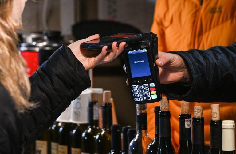 Ręka kobiety zbliżająca smartfon do terminala płatniczego