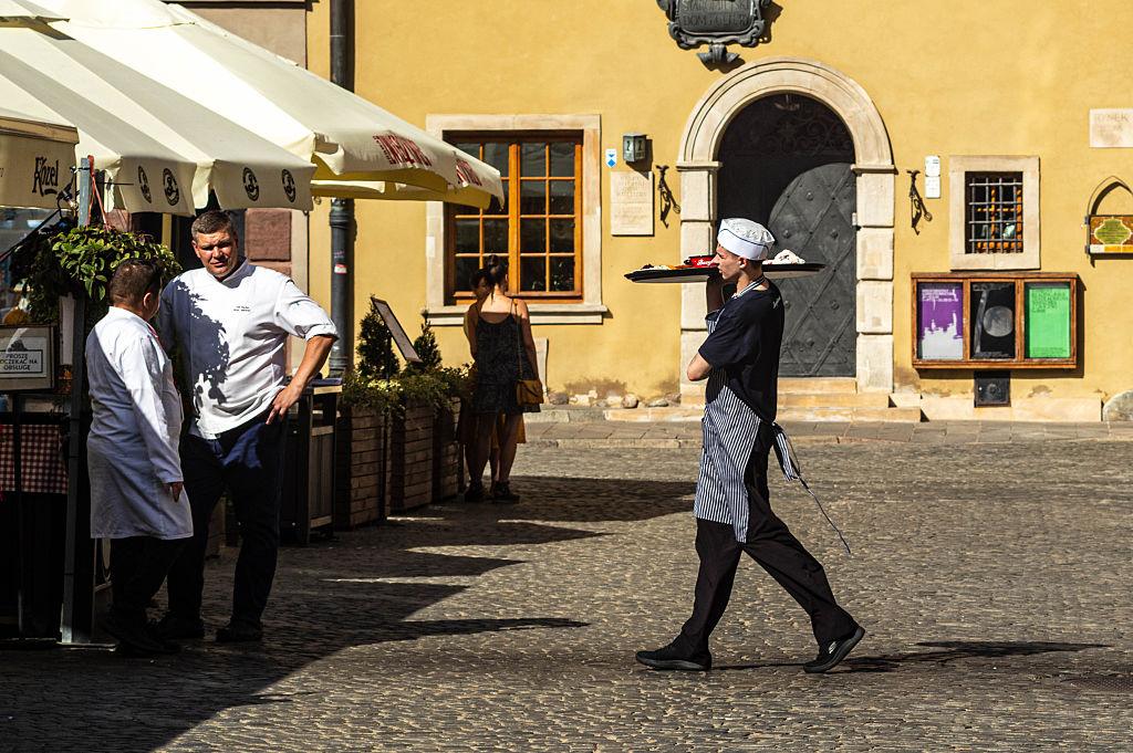 A waiter carries food to the outdoor tables