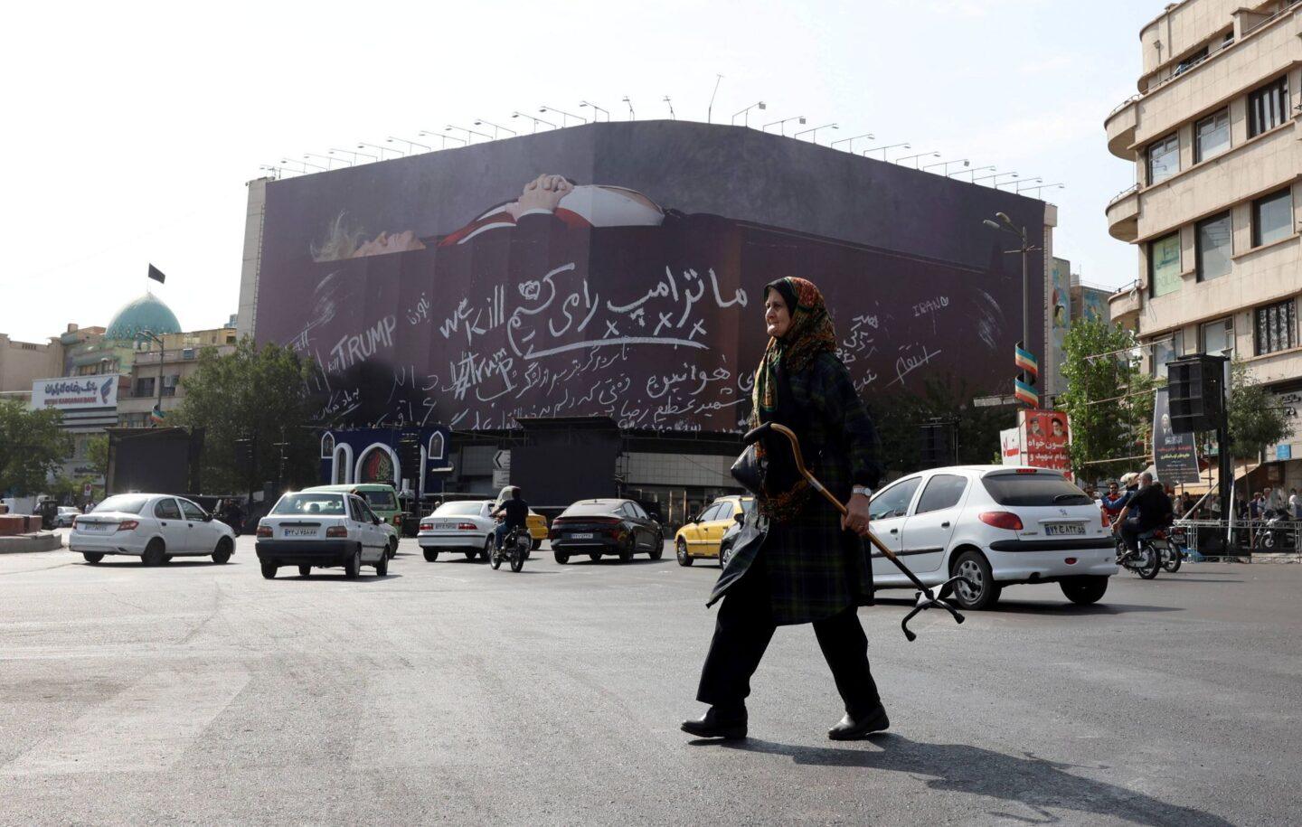 Teheran, kobieta na tle antytrumpowego billboardu, pokazującego prezydenta USA w trumnie