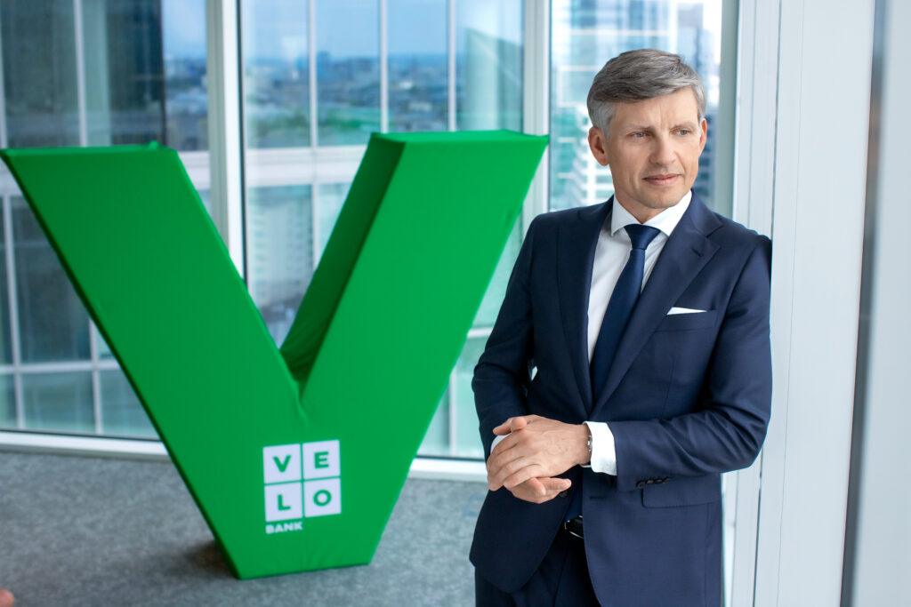 Adam Marciniak, prezes VeloBanku na tle logotypu firmy