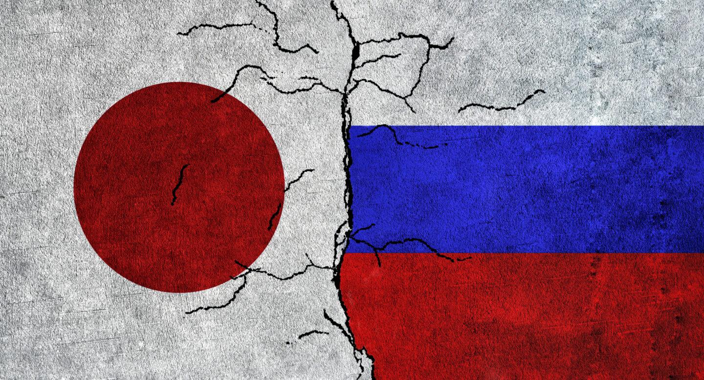 Pokruszone kamienne bloki z flagami Rosji i Japonii