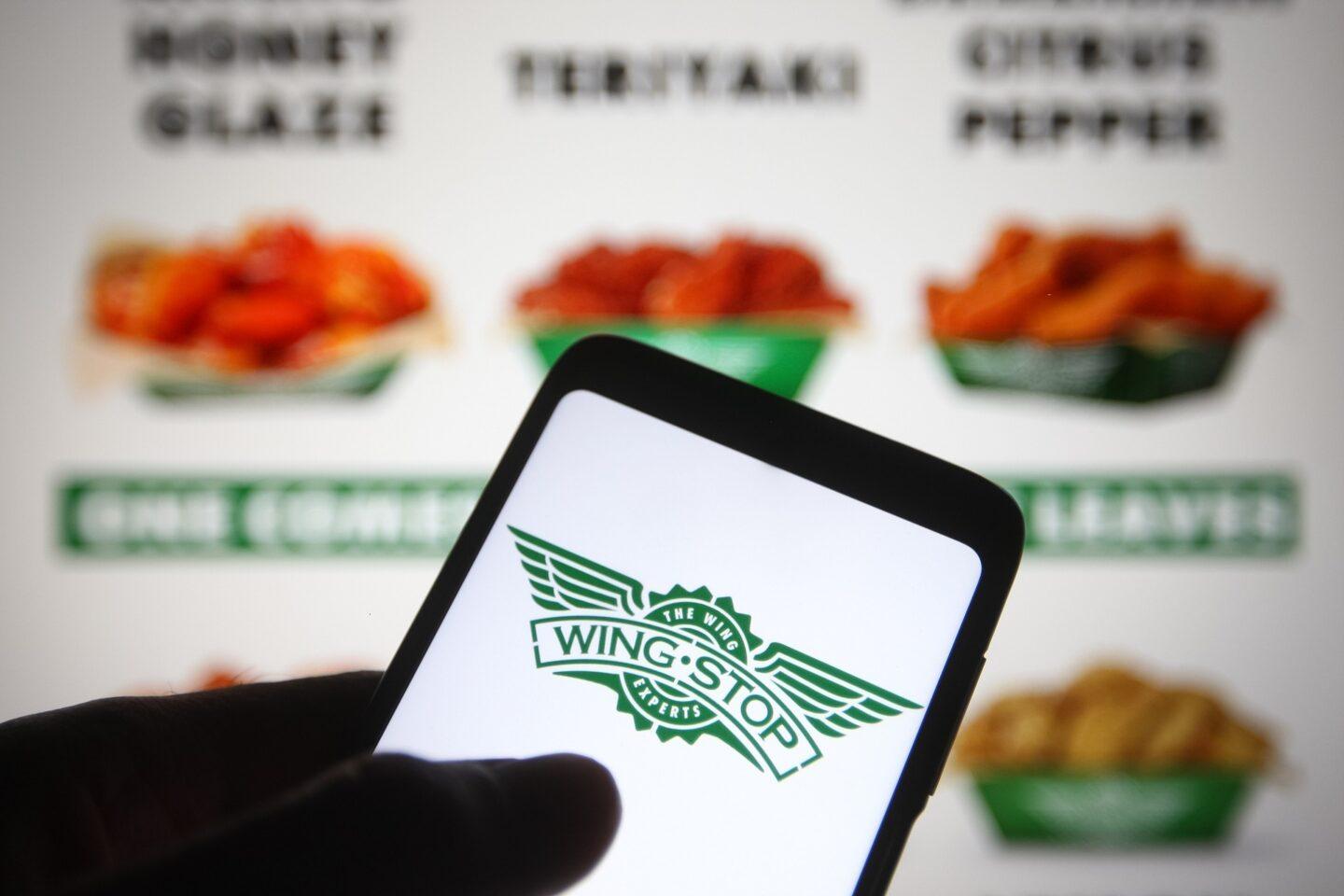 Logo Wingstop na ekranie smartfona na tle menu restauracji. Fot. Pavlo Gonchar/SOPA Images/LightRocket via Getty Images