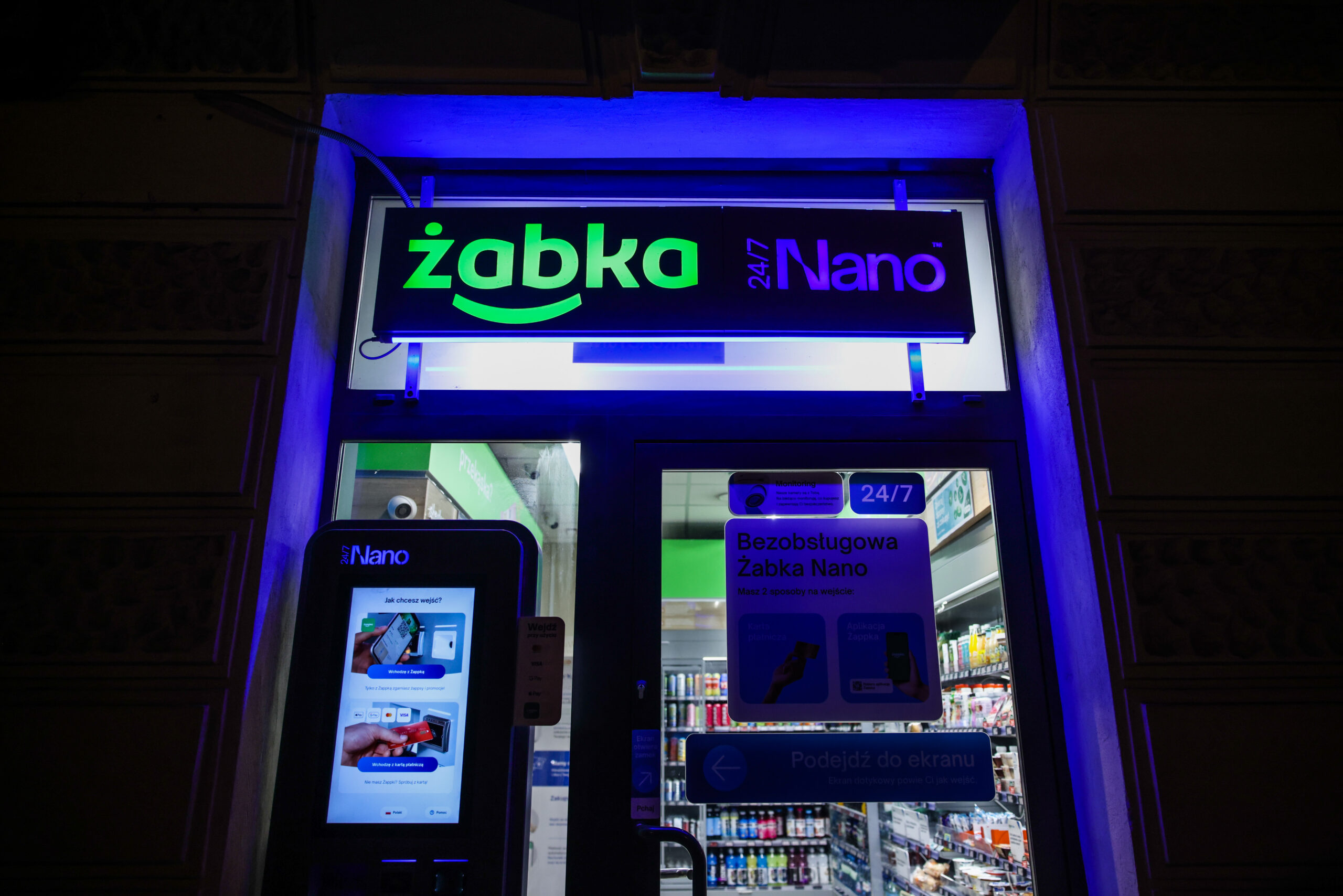 Witryna jednego z samoobsługowych sklepów Żabka Nano nocą.