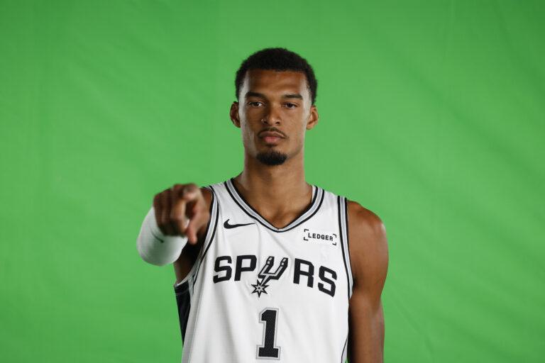 Victor Wembanyama pozuje do zdjęcia na zielonym tle przed nowym sezonem NBA