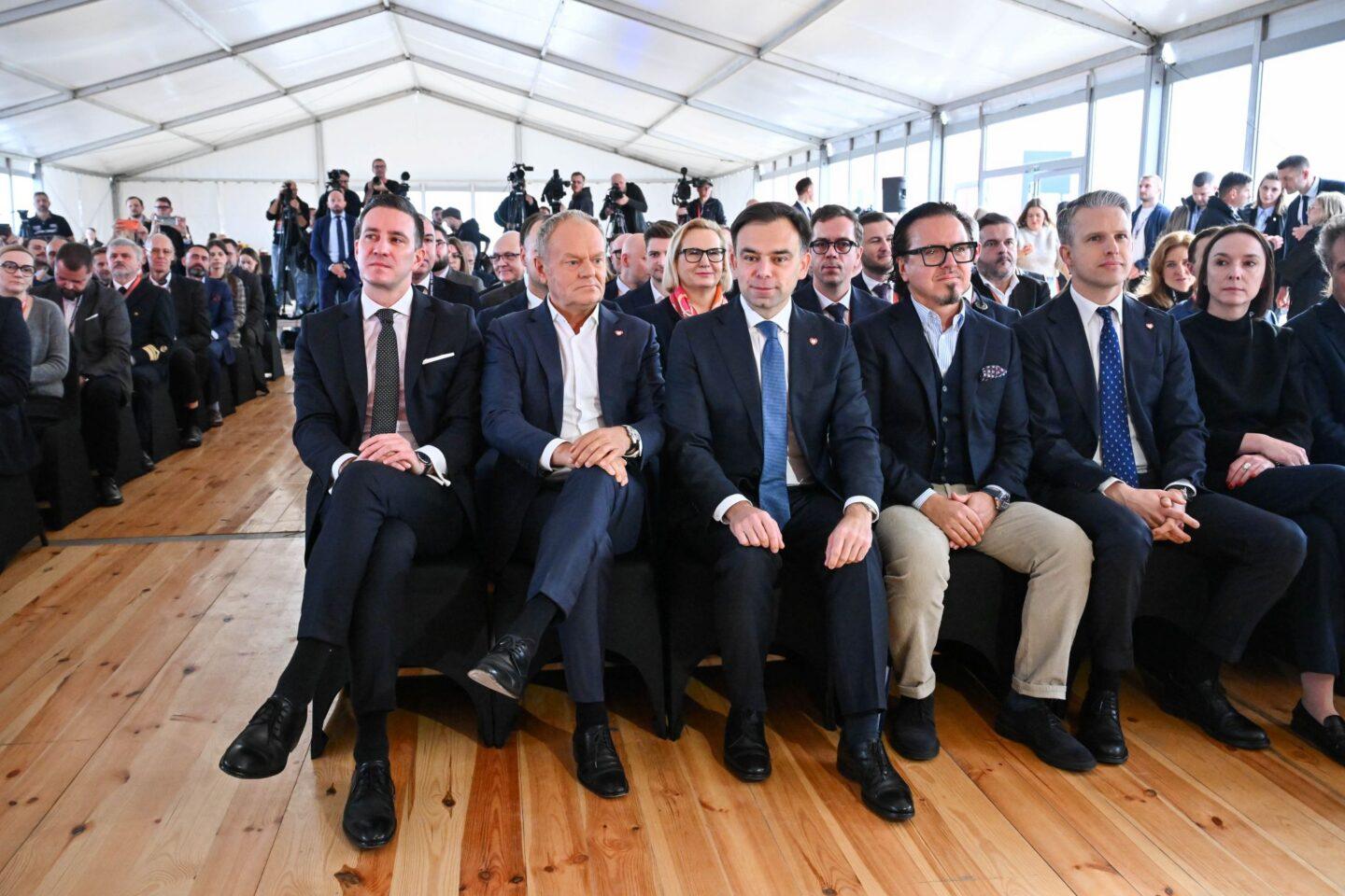 W pierwszym rzędzie: premier Donald Tusk (2L), prezes zarządu Polskiego Funduszu Rozwoju S.A. Mikołaj Raczyński (L), minister finansów i gospodarki Andrzej Domański (3L), minister aktywów państwowych Wojciech Balczun (3P), wiceminister infrastruktury Arkadiusz Marchewka (2P) oraz wiceminister aktywów państwowych Eliza Zeidler (P)
