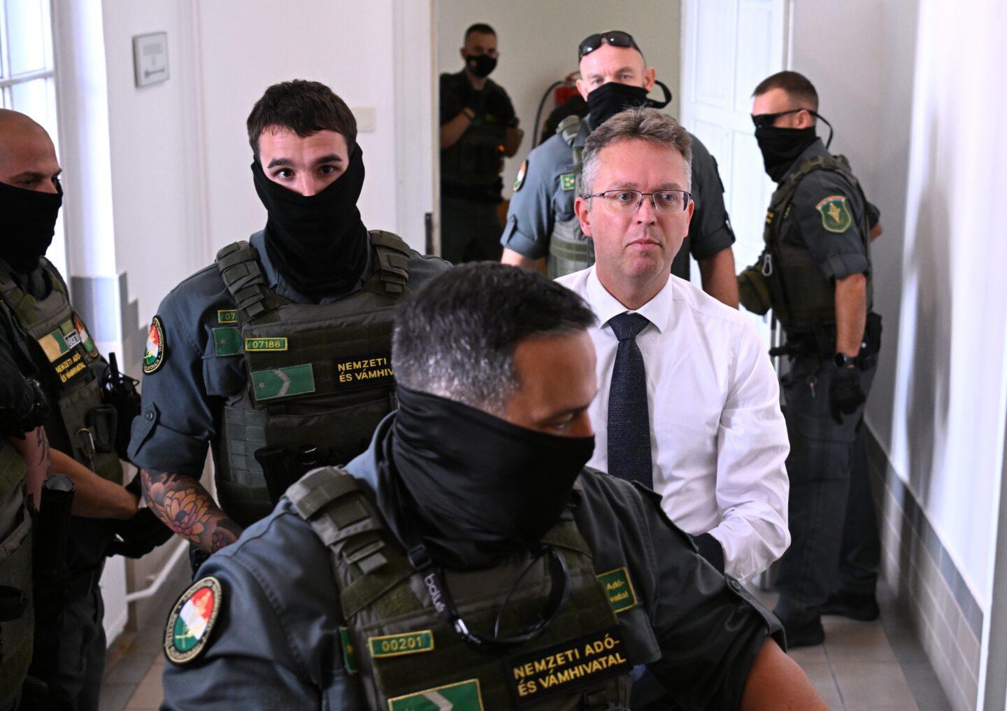 Balázs Hankó, były minister w rządzie Viktora Orbána, przybywa na salę sądową w Kecskemét na Węgrzech w asyście funkcjonariuszy Urzędu Skarbowego i Celnego (NAV).